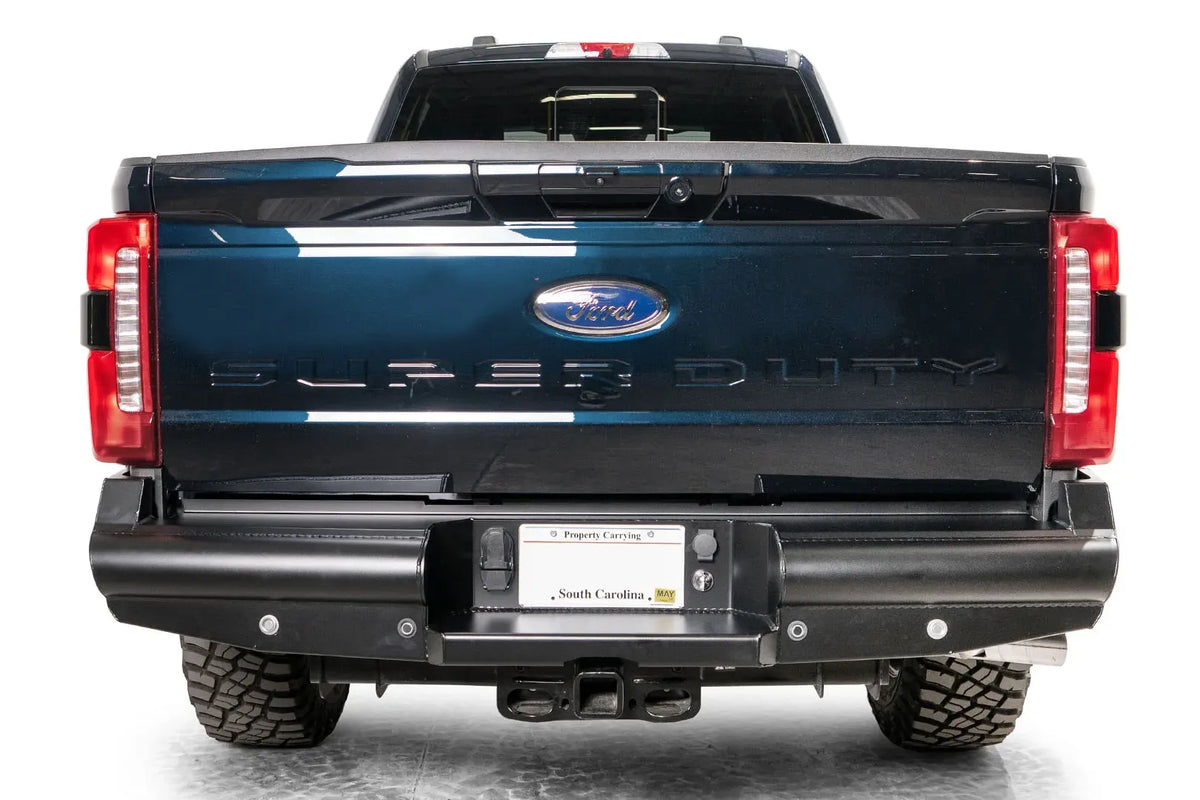 Fab Fours Black Steel Elite rear bumper on a gray and dark blue two-tone Ford Super Duty, straight-on rear view, showing the smooth-plate face, center license plate pocket and receiver hitch opening