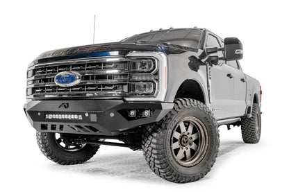Fab Fours Vengeance front bumper on a gray and dark blue two-tone Ford Super Duty, front driver-side three-quarter view, showing the sculpted no-guard face, integrated LED light bar and cube light pockets