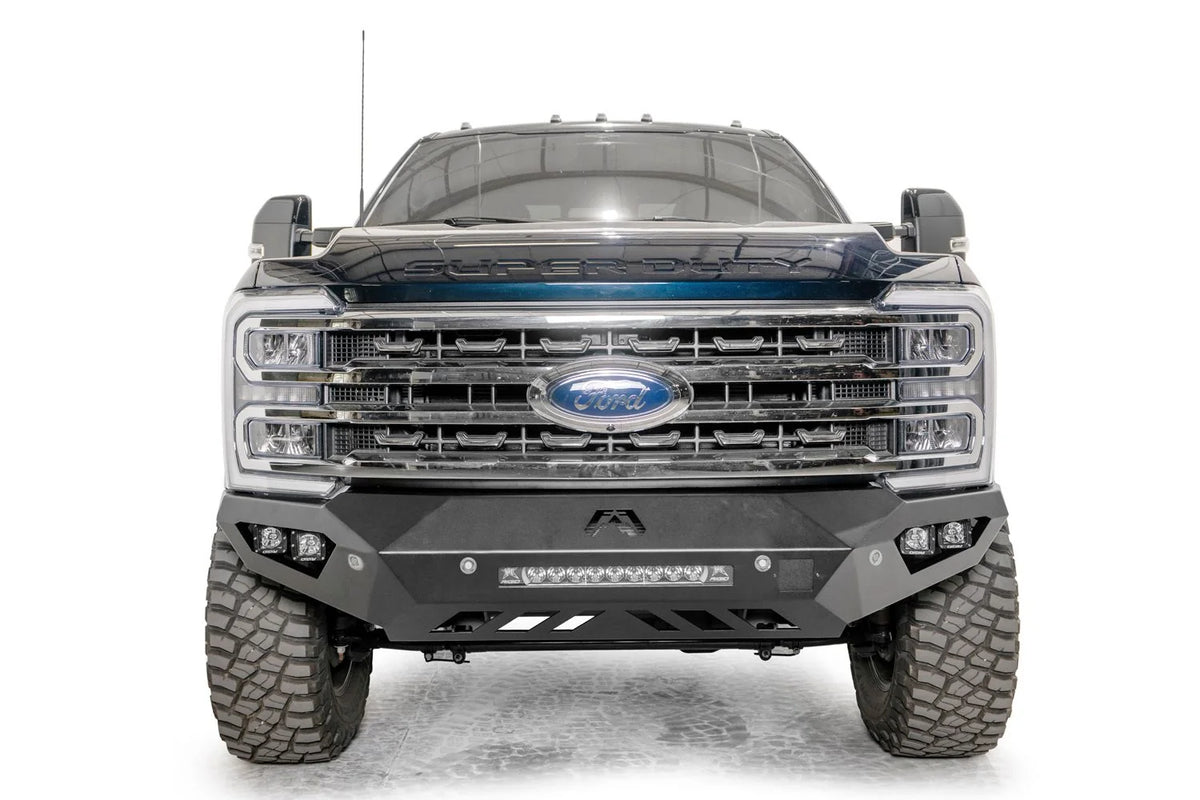 Fab Fours Vengeance front bumper on a gray and dark blue two-tone Ford Super Duty, straight-on front view, showing the sculpted no-guard face, center LED light bar and outboard cube lights
