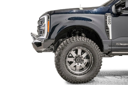 Fab Fours Vengeance front bumper with pre-runner guard on a dark blue Ford Super Duty, close-up of the driver-side corner, showing the pre-runner tube end, bumper wing and wheel-well clearance