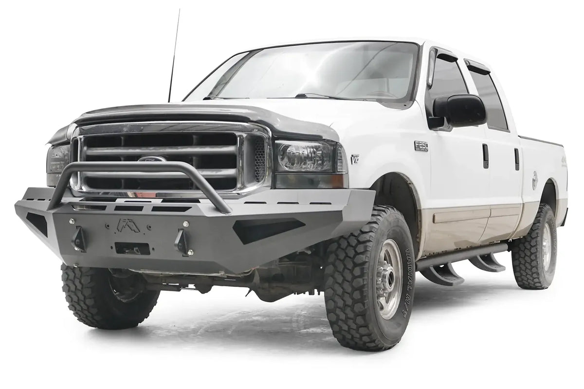 Fab Fours Red Steel front bumper with pre-runner guard on a white and tan two-tone Ford Super Duty F-250, front driver-side three-quarter view, showing the pre-runner hoop, angular bumper face and winch opening