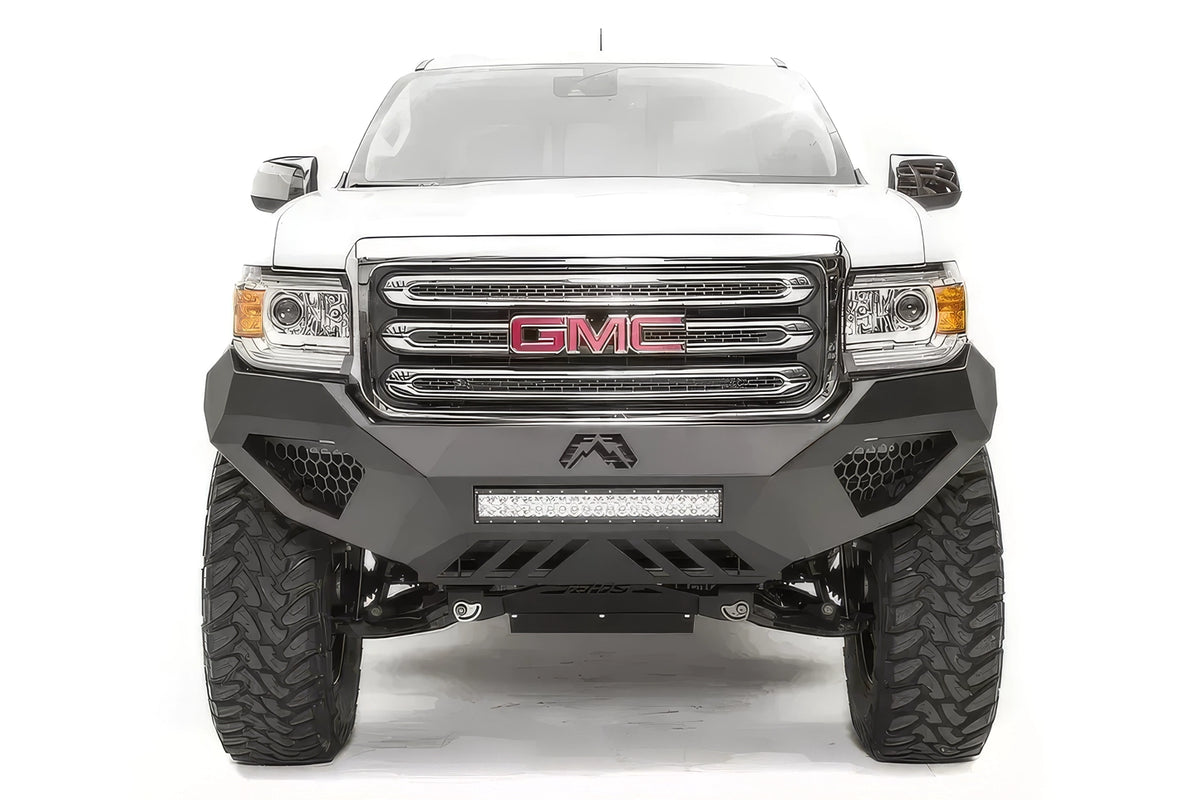 Fab Fours Vengeance front bumper on a white GMC Canyon, straight-on front view, showing the sculpted no-guard face, center LED light bar and honeycomb light pockets