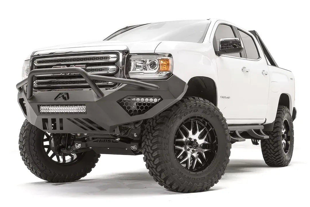 Fab Fours Vengeance front bumper with pre-runner guard on a white GMC Canyon, front passenger-side three-quarter view, showing the pre-runner hoop, integrated LED light bar and honeycomb light pockets