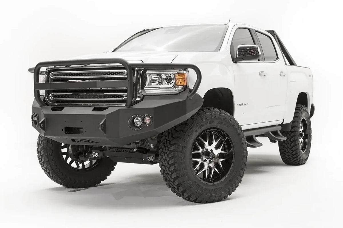 Fab Fours Premium front bumper with full guard on a white GMC Canyon, front passenger-side three-quarter view, showing the full grille guard hoop, winch opening and round fog light cutouts
