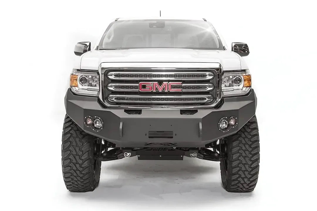 Fab Fours Premium front bumper on a white GMC Canyon, straight-on front view, showing the no-guard winch bumper face, center winch opening and round fog light cutouts