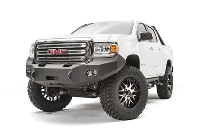 Fab Fours Premium front bumper on a white GMC Canyon, front passenger-side three-quarter view, showing the no-guard winch bumper face, round fog light cutouts and wrapped wings
