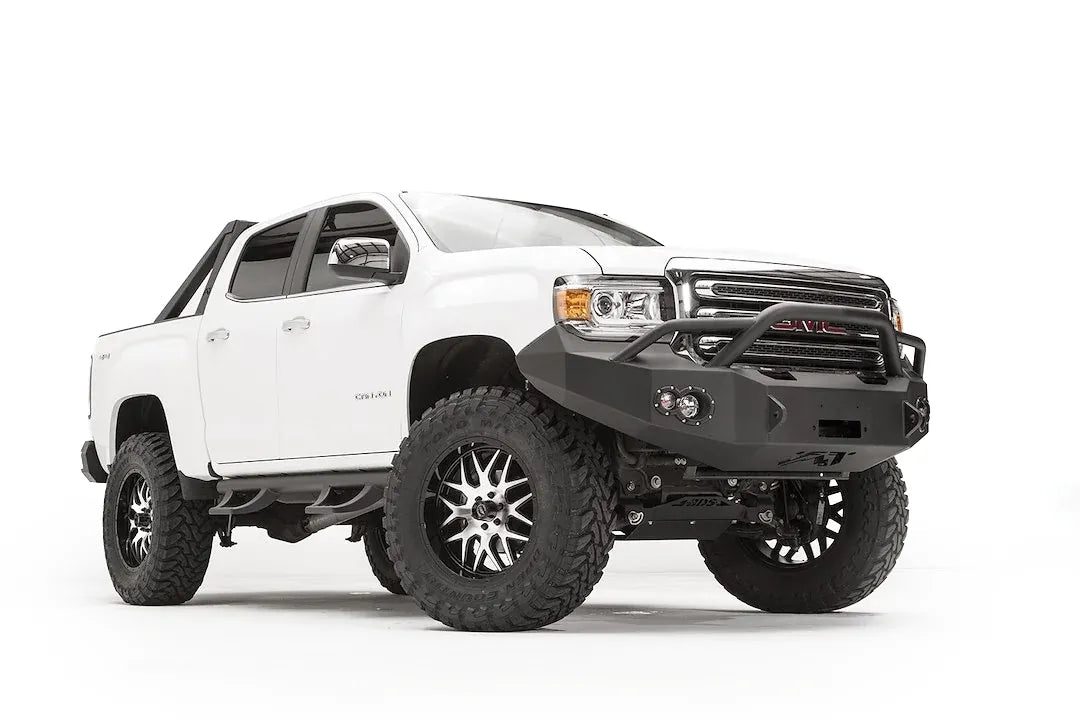 Fab Fours Premium front bumper with pre-runner guard on a white GMC Canyon, front driver-side three-quarter view, showing the pre-runner hoop, winch opening and round fog light cutouts