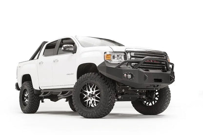 Fab Fours Premium front bumper with pre-runner guard on a white GMC Canyon, front driver-side three-quarter view, showing the pre-runner hoop, winch opening and round fog light cutouts