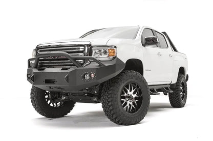Fab Fours Premium front bumper with pre-runner guard on a white GMC Canyon, front passenger-side three-quarter view, showing the pre-runner hoop, winch opening and round fog light cutouts