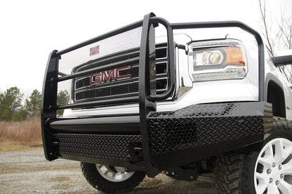 Fab Fours Black Steel front bumper with full guard on a white GMC Sierra 1500, outdoor close-up of the passenger-side corner, showing the guard uprights, mesh grille insert and diamond-plate wing