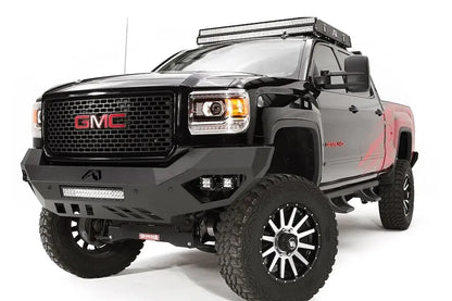 Fab Fours Vengeance front bumper on a black GMC Sierra 2500HD, front driver-side three-quarter view, showing the sculpted no-guard face, integrated LED light bar and cube light pockets