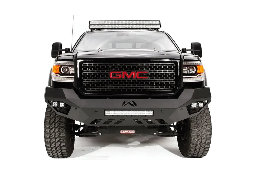 Fab Fours Vengeance front bumper on a black GMC Sierra 2500HD, straight-on front view, showing the sculpted no-guard face, center LED light bar and outboard cube lights