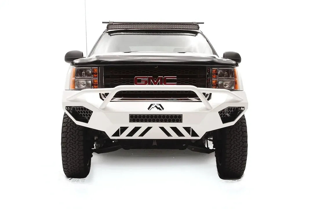Fab Fours Vengeance front bumper with pre-runner guard on a white GMC Sierra 2500HD, straight-on front view, showing the pre-runner hoop, center light bar opening and slotted skid plate