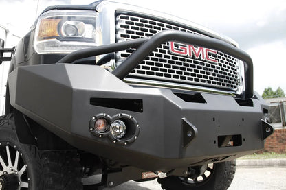 Fab Fours Premium Heavy Duty winch front bumper with pre-runner guard on a black GMC Sierra 2500HD, outdoor close-up of the passenger-side corner, showing the pre-runner tube, round fog light cutouts and shackle tab