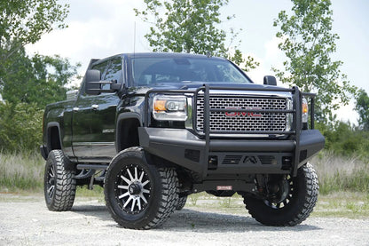 Fab Fours Black Steel Elite front bumper with full guard on a black GMC Sierra 2500HD parked on gravel, front passenger-side three-quarter view, showing the full grille guard, smooth-plate face and wrapped wings