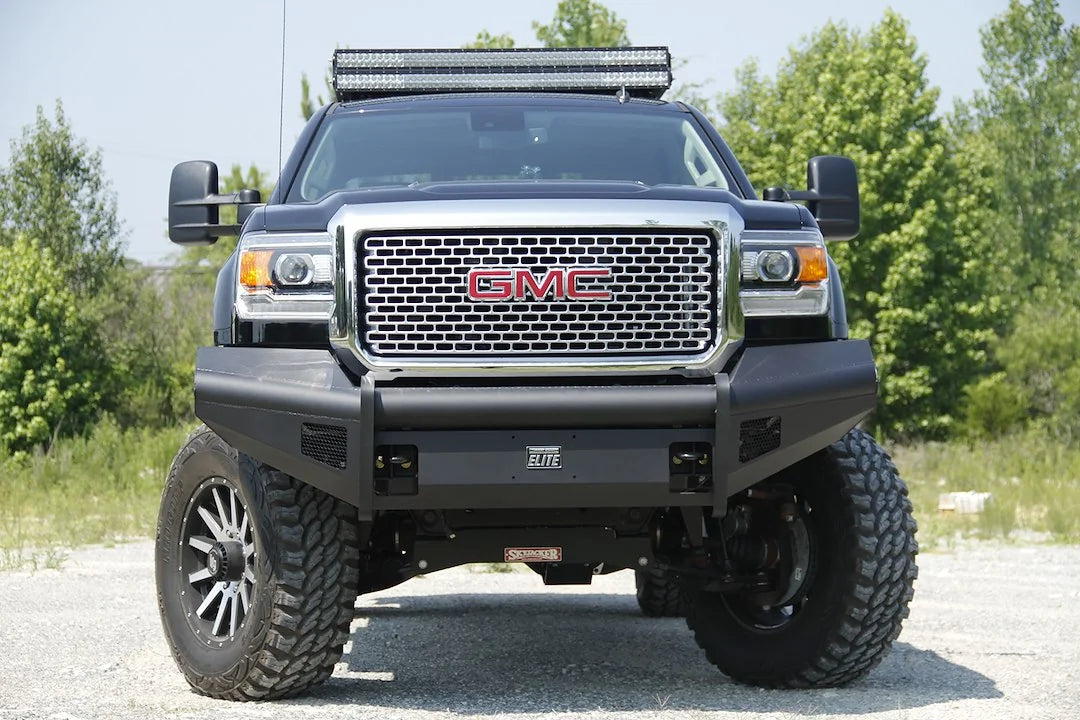 Fab Fours Black Steel Elite front bumper on a black GMC Sierra 2500HD parked on gravel, straight-on front view, showing the no-guard smooth-plate face, Elite badge and mesh light openings