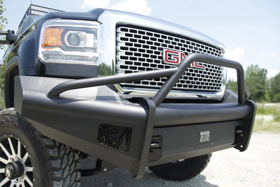 Fab Fours Black Steel Elite front bumper with pre-runner guard on a black GMC Sierra 2500HD, outdoor close-up of the passenger-side corner, showing the pre-runner tube, smooth-plate wing and mesh light opening
