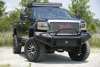 Fab Fours Black Steel Elite front bumper with pre-runner guard on a black GMC Sierra 2500HD parked on gravel, front passenger-side three-quarter view, showing the pre-runner hoop, smooth-plate face and Elite badge