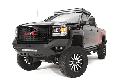 Fab Fours Vengeance front bumper on a black GMC Sierra 2500HD, front driver-side three-quarter view, showing the sculpted no-guard face, LED light bar and angular skid section