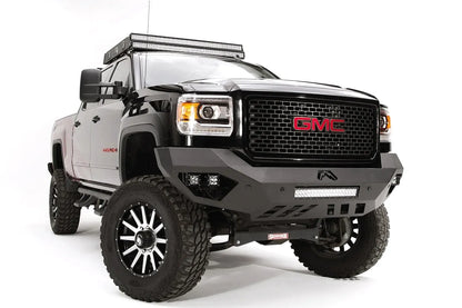 Fab Fours Vengeance front bumper on a black GMC Sierra 2500HD, front passenger-side three-quarter view, showing the sculpted no-guard face, integrated LED light bar and cube light pockets