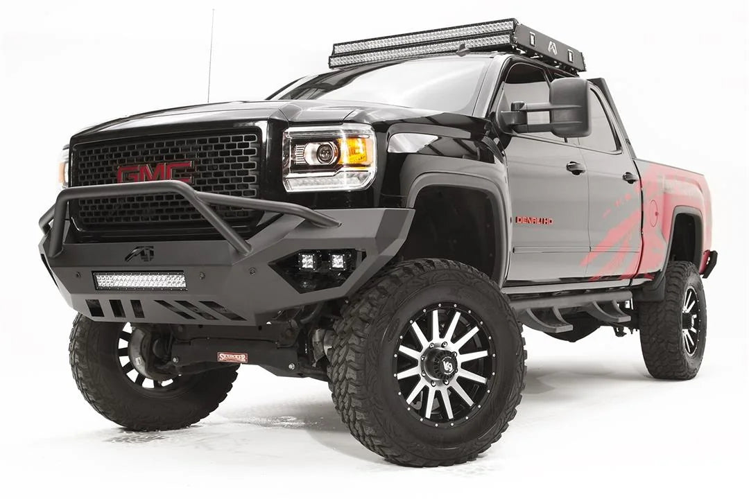 Fab Fours Vengeance front bumper with pre-runner guard on a black GMC Sierra 2500HD, front driver-side three-quarter view, showing the pre-runner hoop, integrated LED light bar and cube light pockets