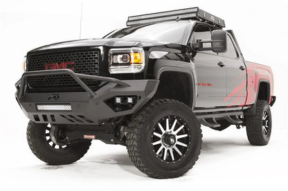 Fab Fours Vengeance front bumper with pre-runner guard on a black GMC Sierra 2500HD, front driver-side three-quarter view, showing the pre-runner hoop, integrated LED light bar and cube light pockets