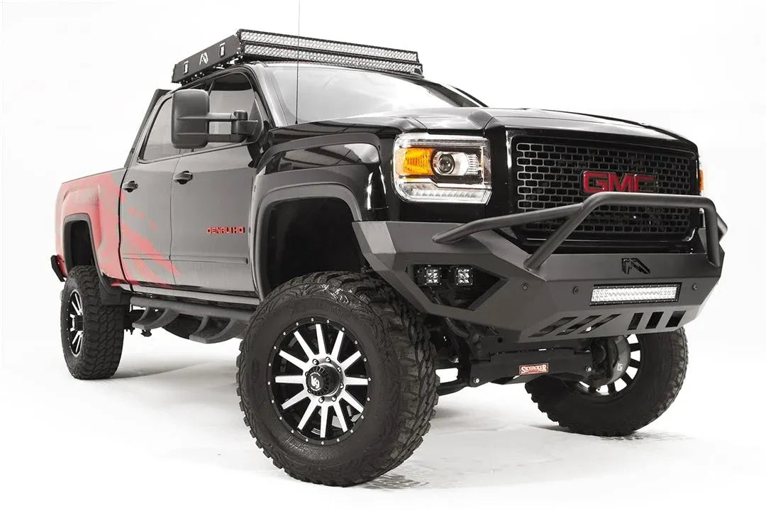 Fab Fours Vengeance front bumper with pre-runner guard on a black GMC Sierra 2500HD, front passenger-side three-quarter view, showing the pre-runner hoop, LED light bar and angular skid section