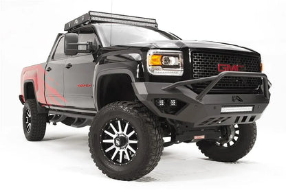 Fab Fours Vengeance front bumper with pre-runner guard on a black GMC Sierra 2500HD, front passenger-side three-quarter view, showing the pre-runner hoop, LED light bar and angular skid section