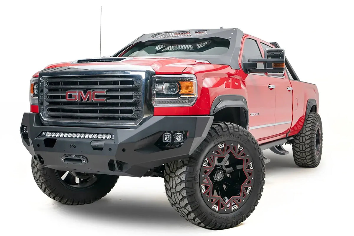Fab Fours Matrix front bumper on a red GMC Sierra 2500HD, front driver-side three-quarter view, showing the no-guard winch bumper face, LED light bar and winch fairlead opening