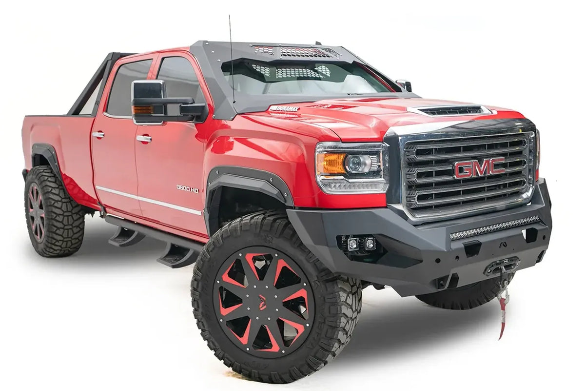 Fab Fours Matrix front bumper on a red GMC Sierra 2500HD, front passenger-side three-quarter view, showing the no-guard winch bumper face, LED light bar and cube light pockets