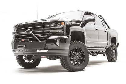 Fab Fours winch mount on a black and gray Chevrolet Silverado 1500, front driver-side three-quarter view, showing tubular hoop, winch plate, low-profile mounting under the factory bumper