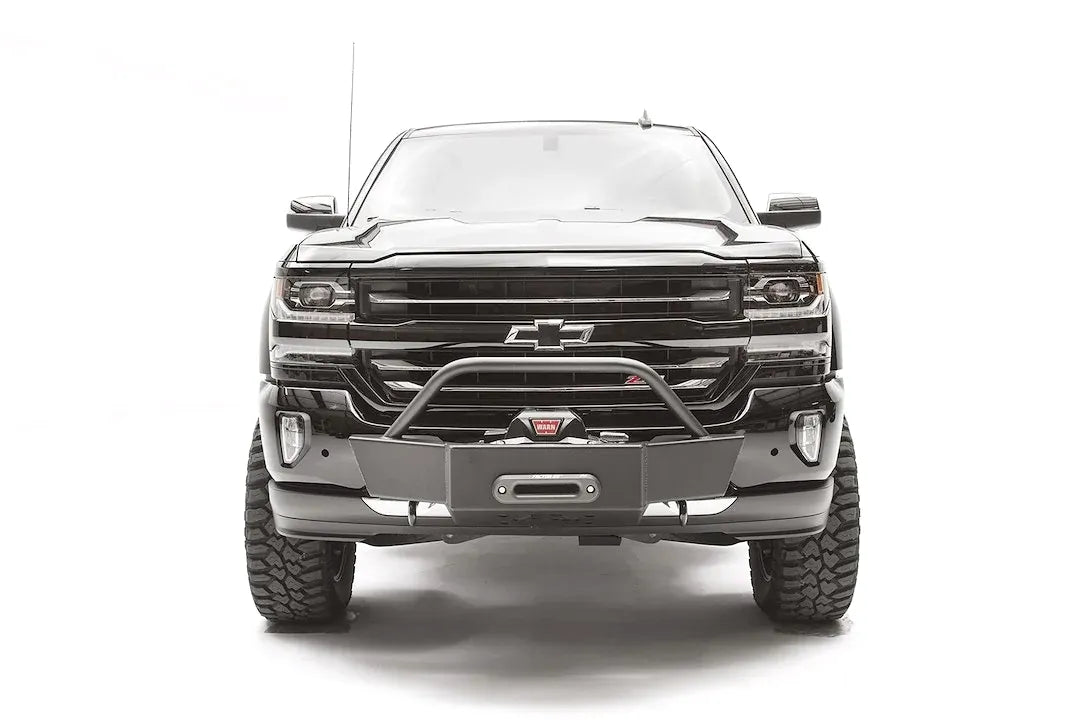 Fab Fours winch mount on a black and gray Chevrolet Silverado 1500, straight-on front view, showing tubular hoop, winch plate, low-profile mounting under the factory bumper