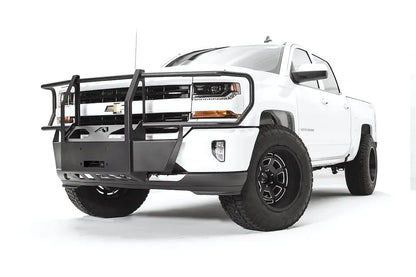 Fab Fours winch mount with full guard on a white Chevrolet Silverado 1500, front driver-side three-quarter view, showing full grille guard uprights, winch plate, wraparound headlight hoops