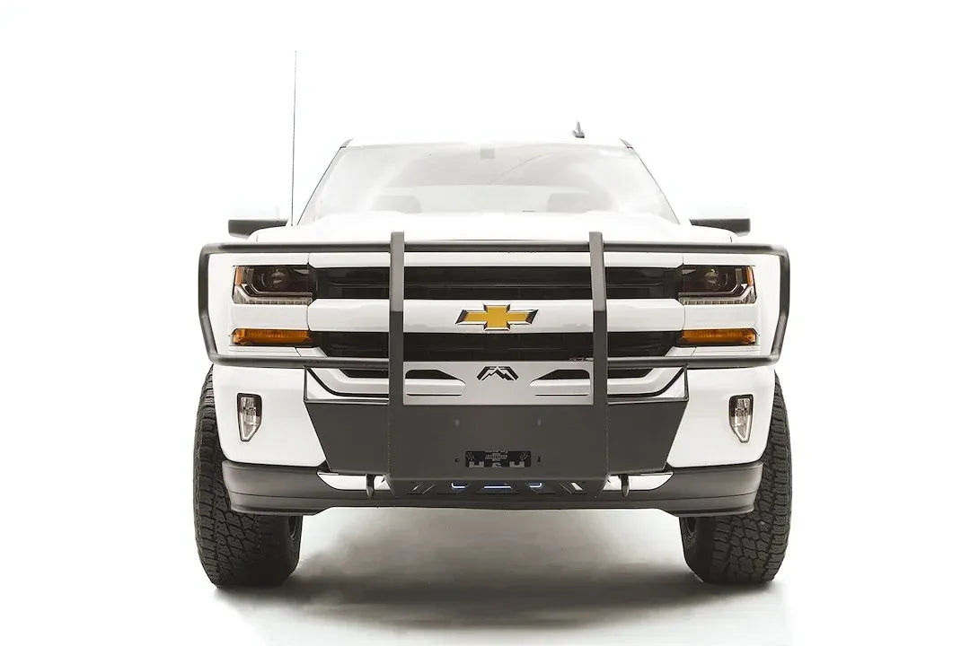 Fab Fours winch mount with full guard on a white Chevrolet Silverado 1500, straight-on front view, showing full grille guard uprights, winch plate, wraparound headlight hoops