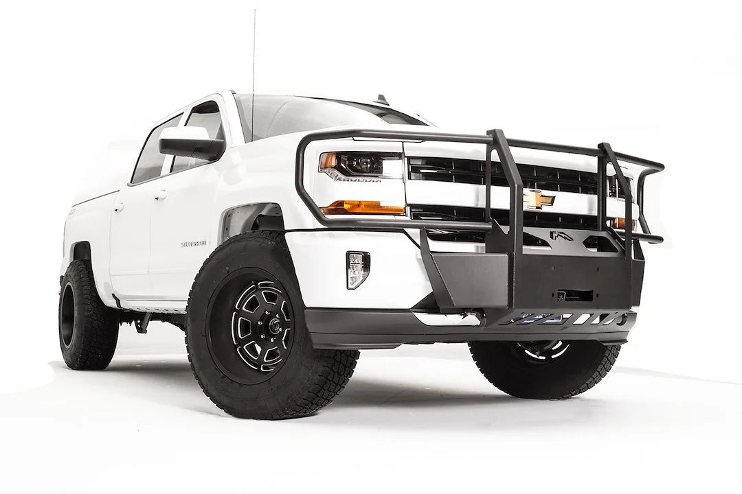 Fab Fours winch mount with full guard on a white Chevrolet Silverado 1500, front passenger-side three-quarter view, showing full grille guard uprights, winch plate, wraparound headlight hoops