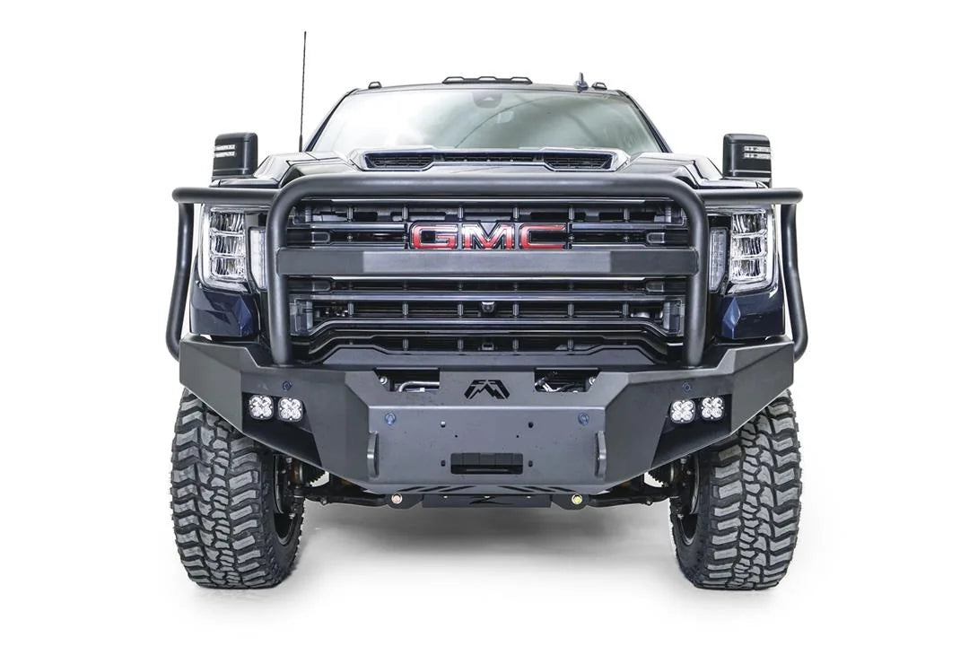 Fab Fours Premium Winch front bumper with full guard on a blue and gray GMC Sierra 2500HD/3500HD, straight-on front view, showing full guard hoop, winch mount opening, cube light pods, angled end caps