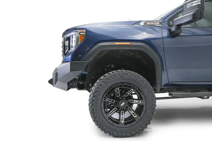 Fab Fours Premium Winch front bumper on a blue and gray GMC Sierra 2500HD/3500HD, close-up of the front corner, showing bumper end cap profile, wheel-well clearance