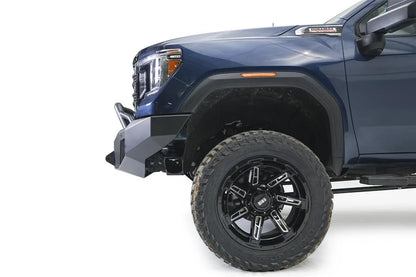 Fab Fours Premium Winch front bumper with pre-runner guard on a blue and gray GMC Sierra 2500HD/3500HD, close-up of the front corner, showing pre-runner hoop, bumper end cap profile, wheel-well clearance