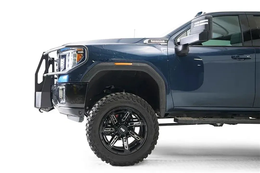 Fab Fours winch mount with full guard on a blue and gray GMC Sierra 2500HD/3500HD, close-up of the front corner, showing full guard side hoop, winch mount profile, wheel-well clearance