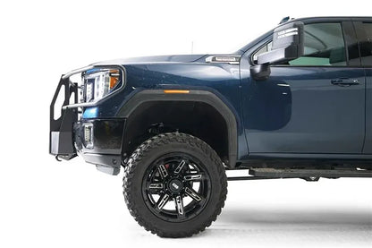 Fab Fours winch mount with full guard on a blue and gray GMC Sierra 2500HD/3500HD, close-up of the front corner, showing full guard side hoop, winch mount profile, wheel-well clearance