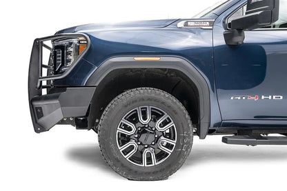 Fab Fours Black Steel Elite front bumper with full guard on a blue GMC Sierra 2500HD/3500HD, close-up of the front corner, showing full guard side hoop, bumper end profile, wheel-well clearance