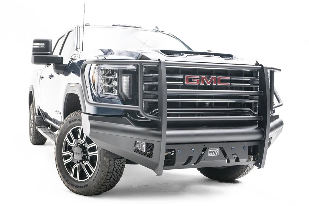 Fab Fours Black Steel Elite front bumper with full guard on a blue GMC Sierra 2500HD/3500HD, front passenger-side three-quarter view, showing full grille guard, Elite badge, slotted skid plate, mesh end inserts