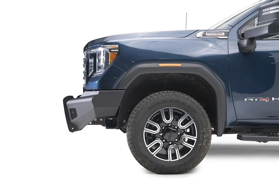 Fab Fours Black Steel Elite front bumper on a blue GMC Sierra 2500HD/3500HD, close-up of the front corner, showing bumper end profile, mesh insert, wheel-well clearance