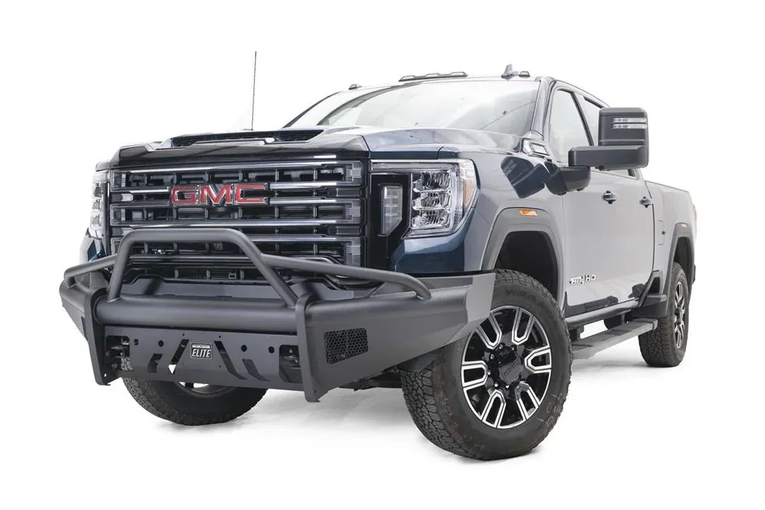 Fab Fours Black Steel Elite front bumper with pre-runner guard on a blue GMC Sierra 2500HD/3500HD, front driver-side three-quarter view, showing pre-runner hoop, Elite badge, slotted skid plate, mesh end inserts