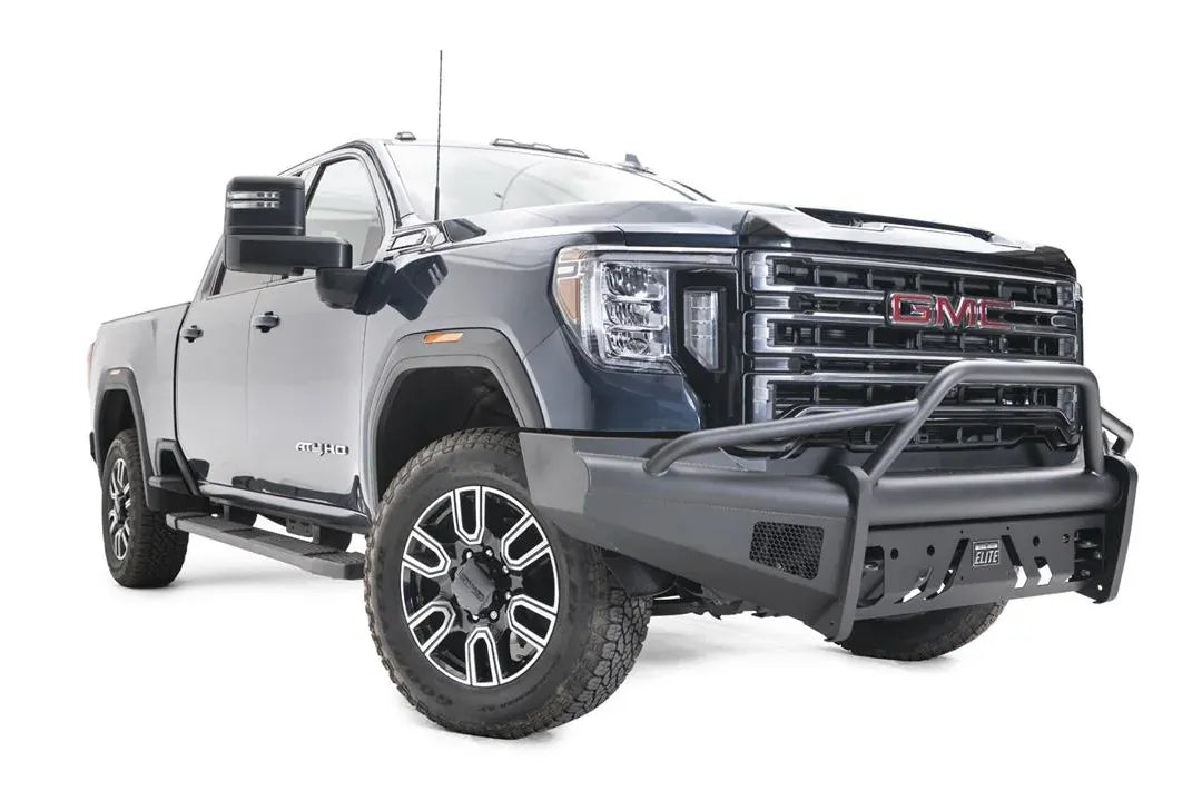 Fab Fours Black Steel Elite front bumper with pre-runner guard on a blue GMC Sierra 2500HD/3500HD, front passenger-side three-quarter view, showing pre-runner hoop, Elite badge, slotted skid plate, mesh end inserts