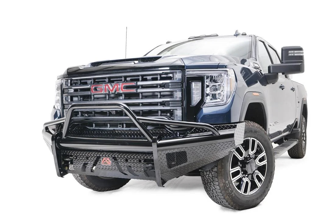 Fab Fours Black Steel front bumper with pre-runner guard on a blue GMC Sierra 2500HD/3500HD, front driver-side three-quarter view, showing pre-runner hoop, diamond-plate finish, mesh end inserts, Fab Fours badge
