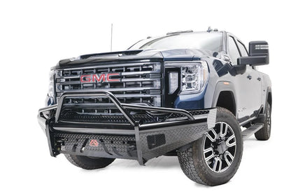 Fab Fours Black Steel front bumper with pre-runner guard on a blue GMC Sierra 2500HD/3500HD, front driver-side three-quarter view, showing pre-runner hoop, diamond-plate finish, mesh end inserts, Fab Fours badge