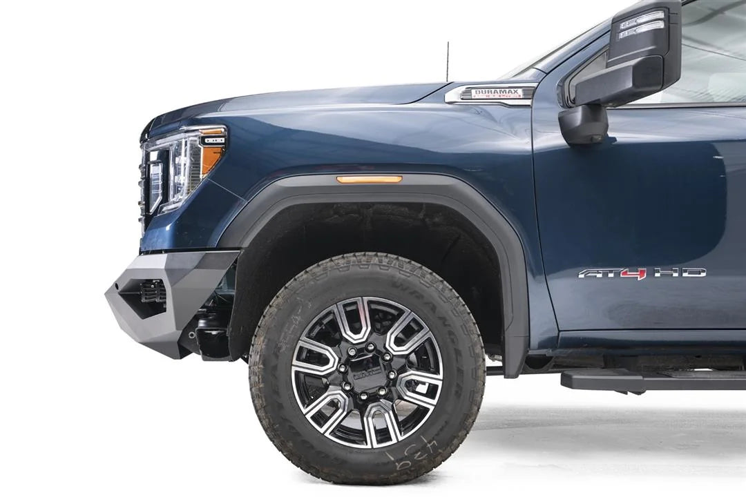 Fab Fours Vengeance front bumper on a blue GMC Sierra 2500HD/3500HD, close-up of the front corner, showing angular end cap, bumper profile, wheel-well clearance