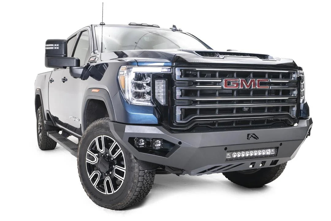 Fab Fours Vengeance front bumper on a blue GMC Sierra 2500HD/3500HD, front passenger-side three-quarter view, showing integrated light bar, cube light pods, angular skid plate