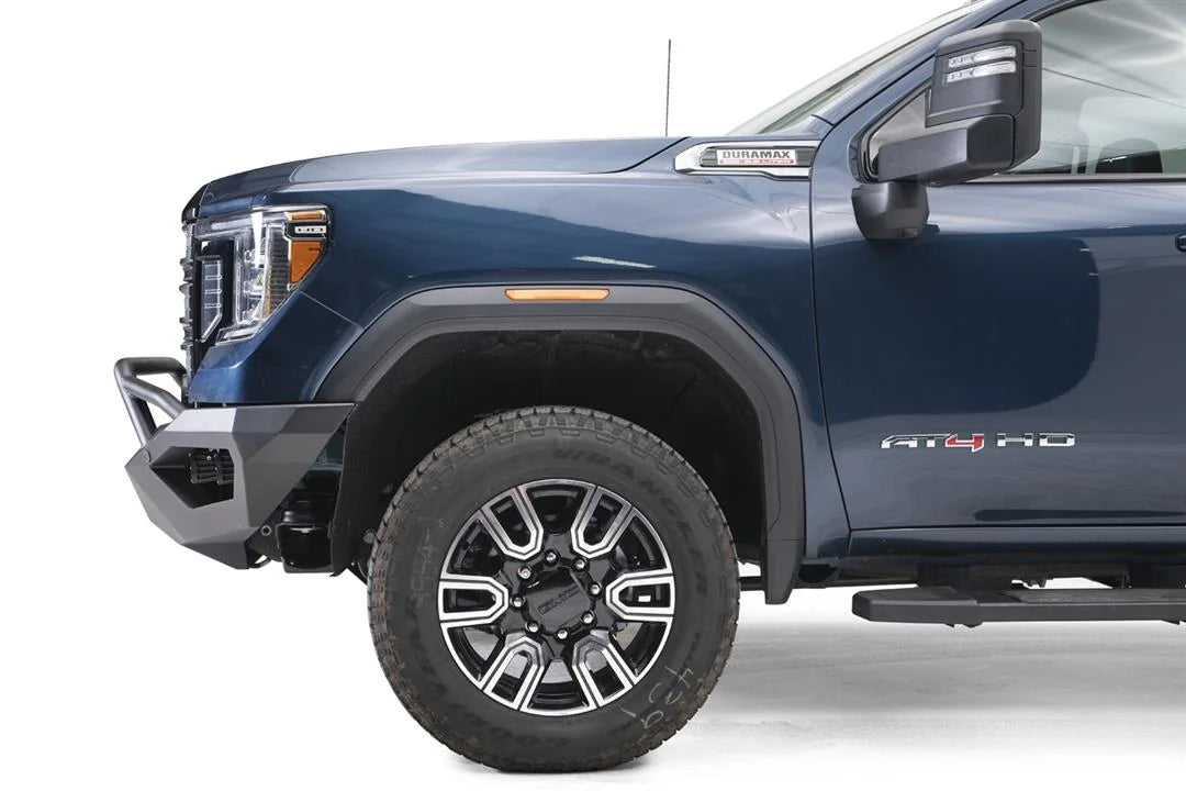 Fab Fours Vengeance front bumper with pre-runner guard on a blue GMC Sierra 2500HD/3500HD, close-up of the front corner, showing pre-runner hoop, angular end cap, wheel-well clearance